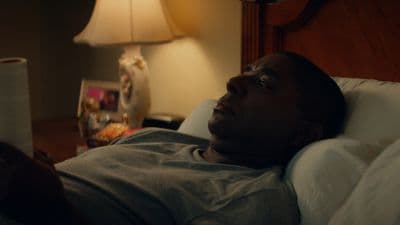 a man laying in a bed next to a lamp
