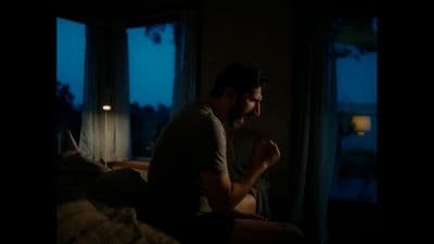 a man sitting on a bed in a dark room