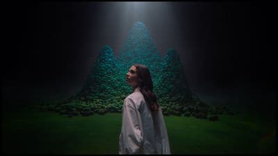 a woman standing in front of a green mountain