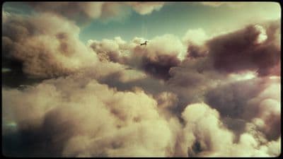 a plane flying through a cloudy blue sky