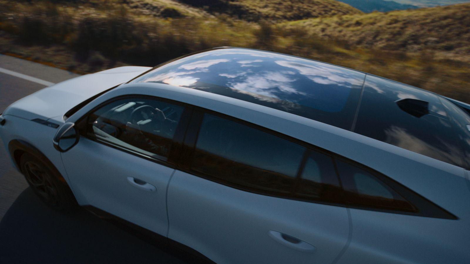 a white car driving down a road with mountains in the background