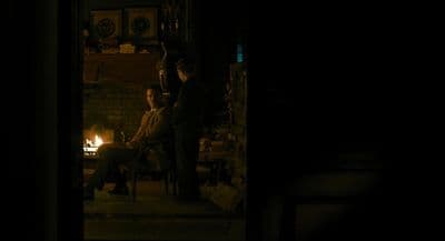 a man and a woman sitting in a chair in front of a fire