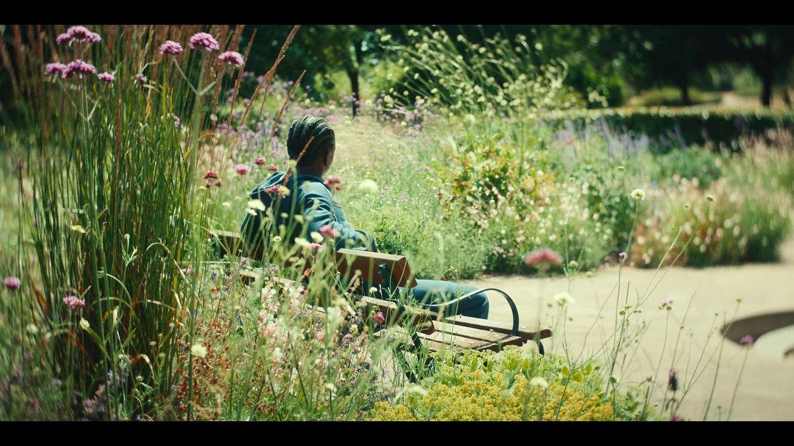a person sitting on a bench in a garden