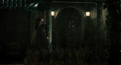 a woman standing in the rain holding an umbrella