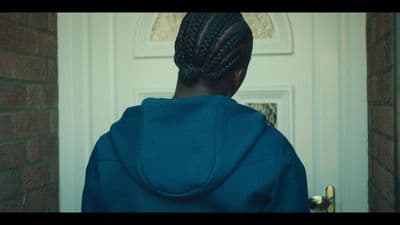 a woman in a blue hoodie standing in front of a door