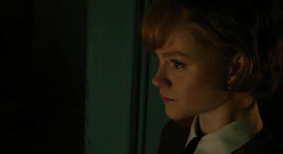 a woman in a suit and tie looking off into the distance