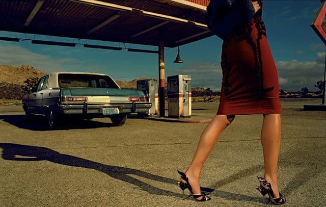 a woman in a red dress is standing in front of a gas station
