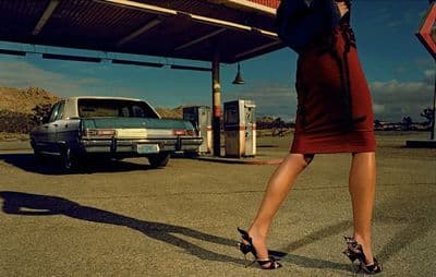 a woman in a red dress is standing in front of a gas station