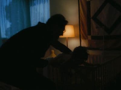a man standing next to a baby in a crib