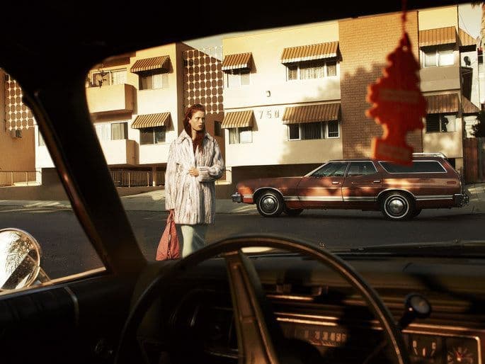 a woman standing next to a car on a street