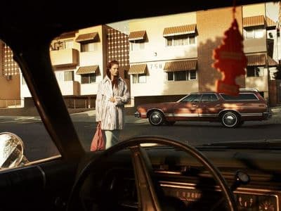 a woman standing next to a car on a street