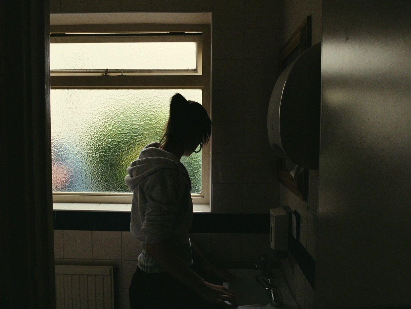 a woman standing in a bathroom next to a window