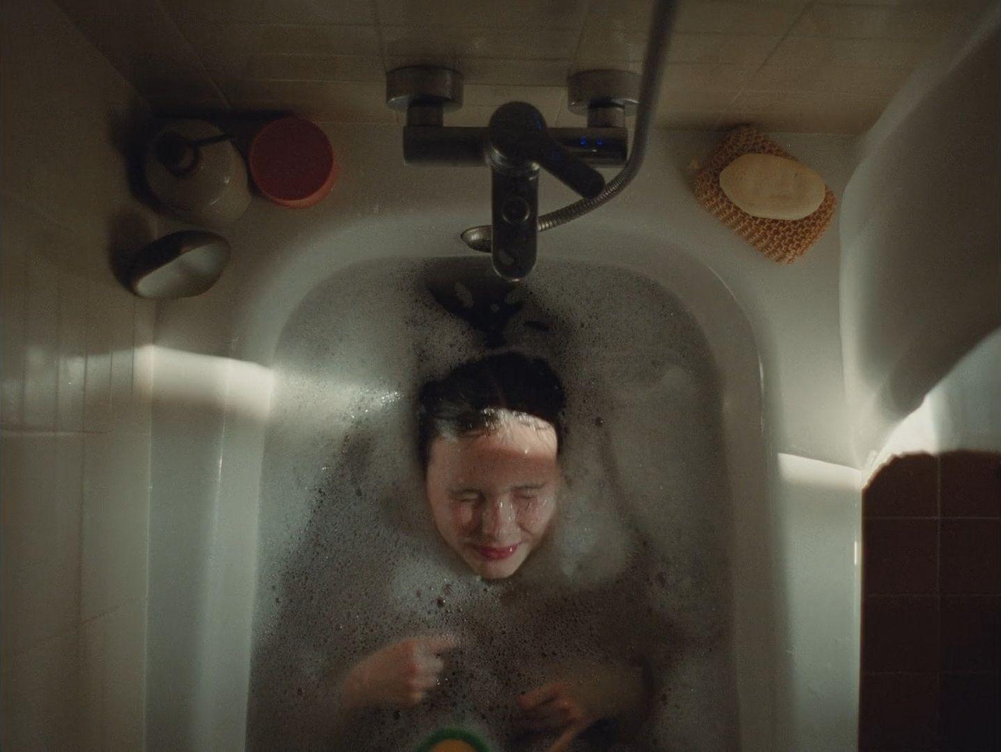 a woman in a bathtub with soap on her face