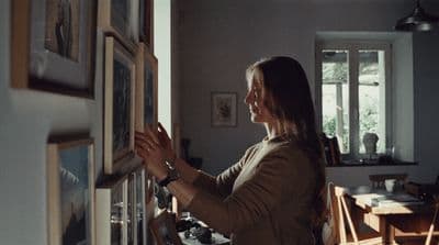 a woman looking at pictures on a wall