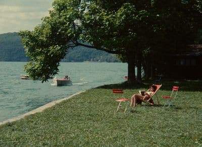 a woman lounging on a lawn next to a lake