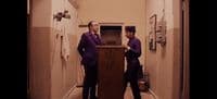two men in purple suits standing in a hallway