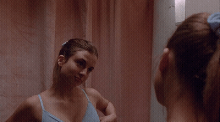 a woman is brushing her teeth in front of a mirror