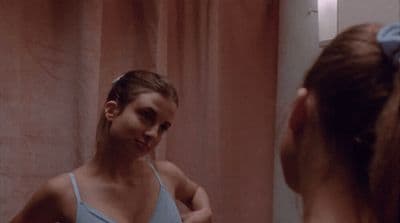 a woman is brushing her teeth in front of a mirror