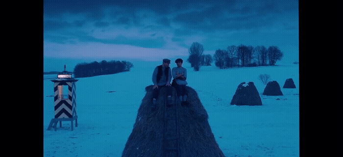 two people sitting on a fence in the snow