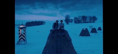 two people sitting on a fence in the snow