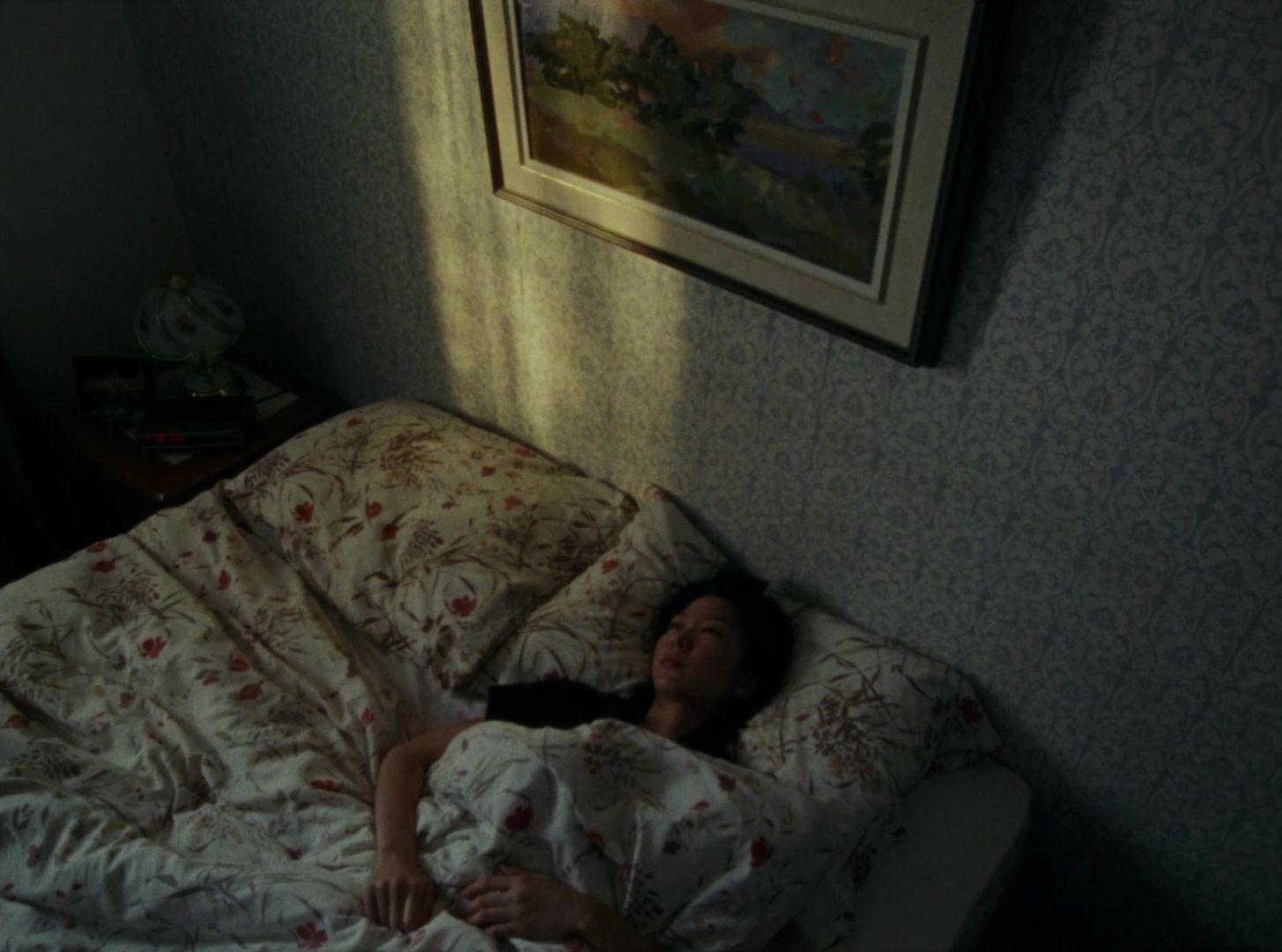 a woman laying in a bed under a painting