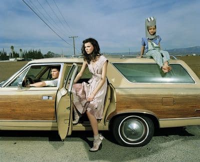 a woman sitting in the driver's seat of a car next to a man