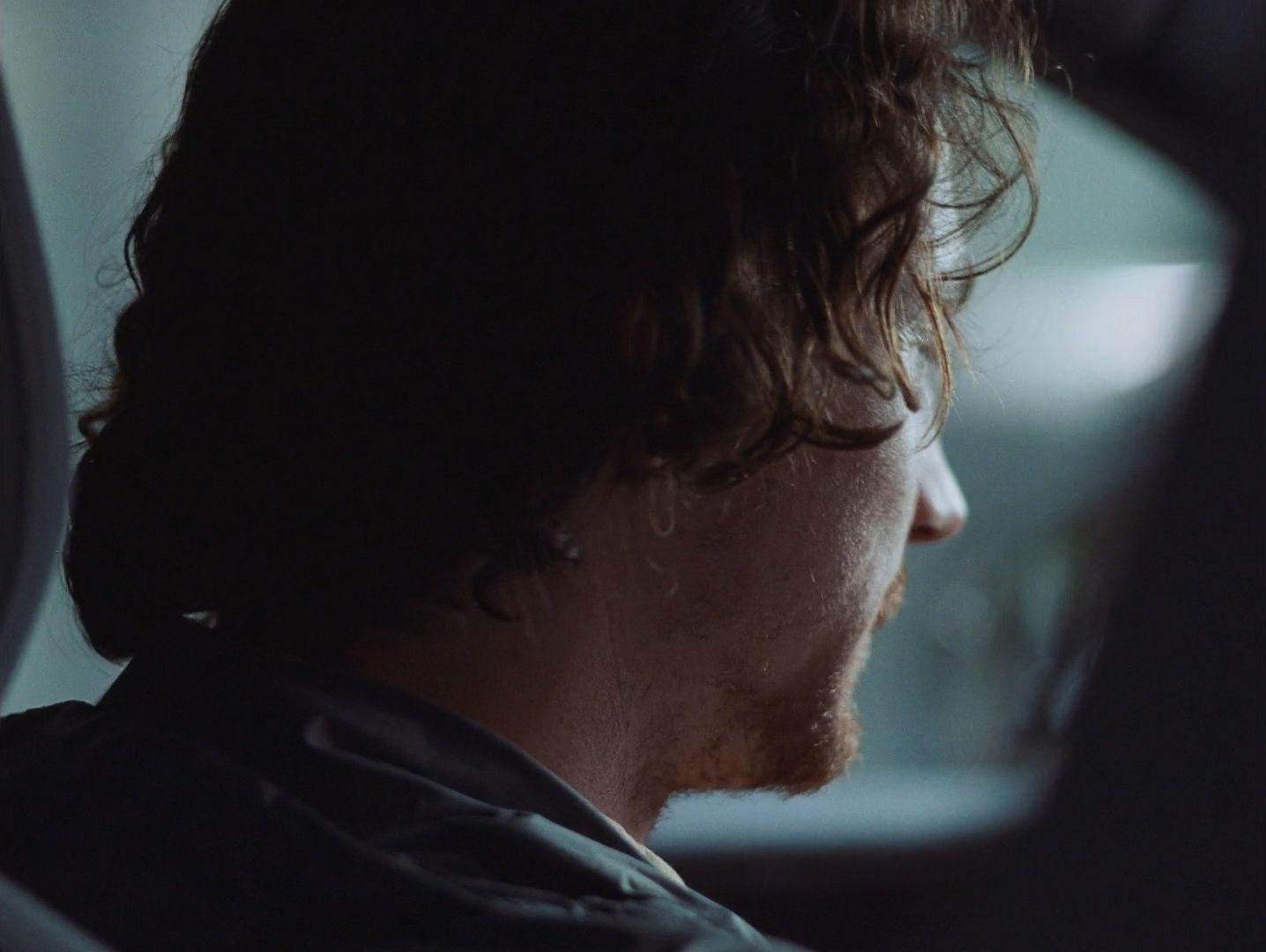 a man sitting in a car looking out the window