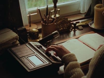 a person typing on a typewriter in front of a window