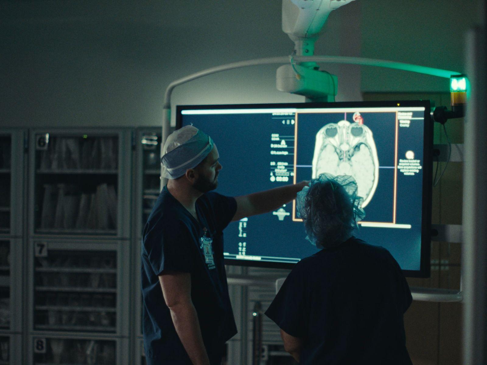 a man and a woman standing in front of a medical monitor