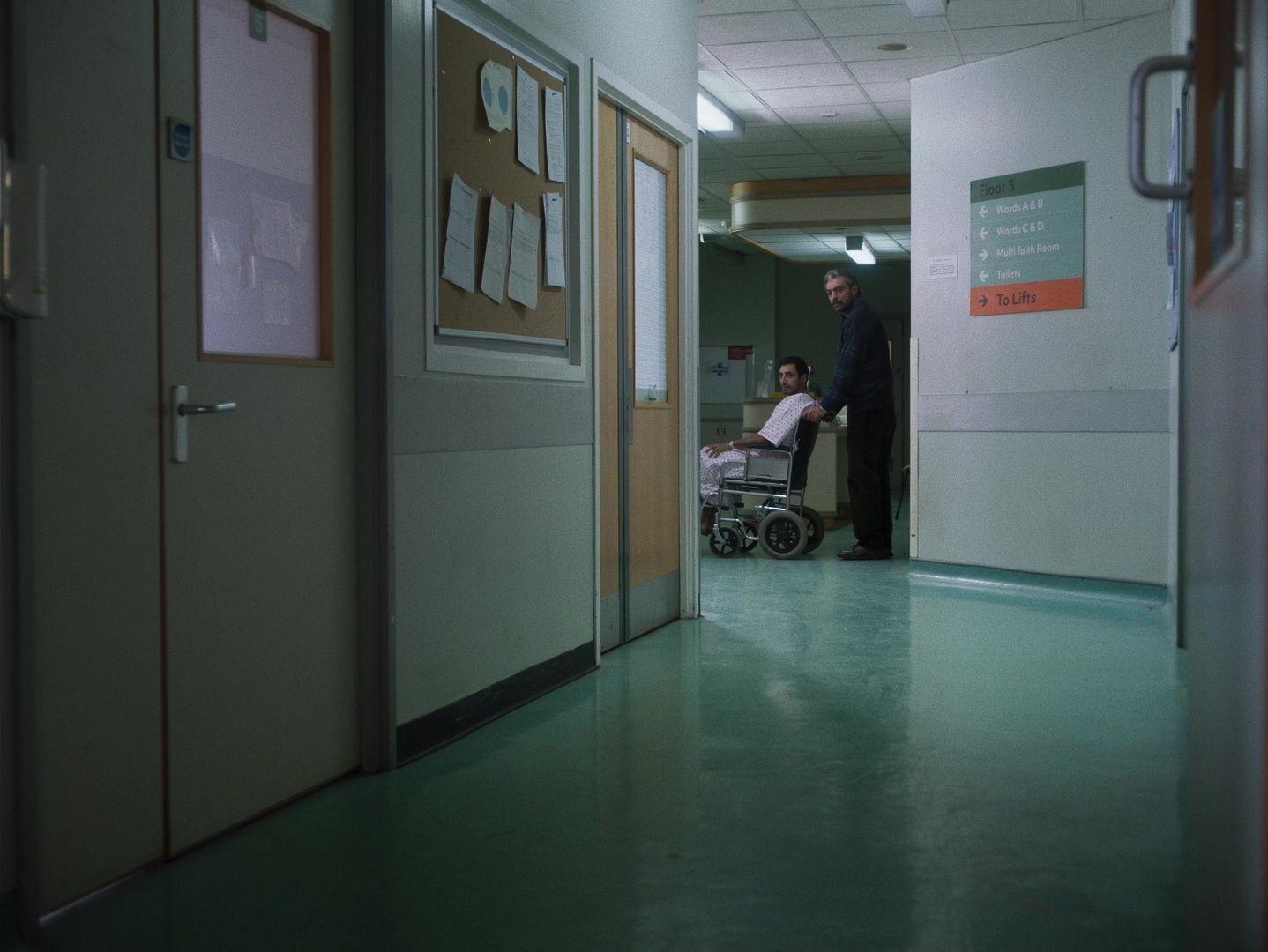 a man standing in a hallway next to a woman in a wheel chair