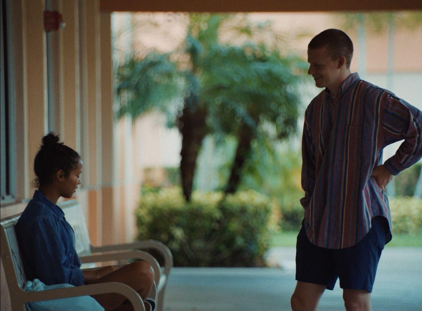 a man standing next to a woman sitting on a bench