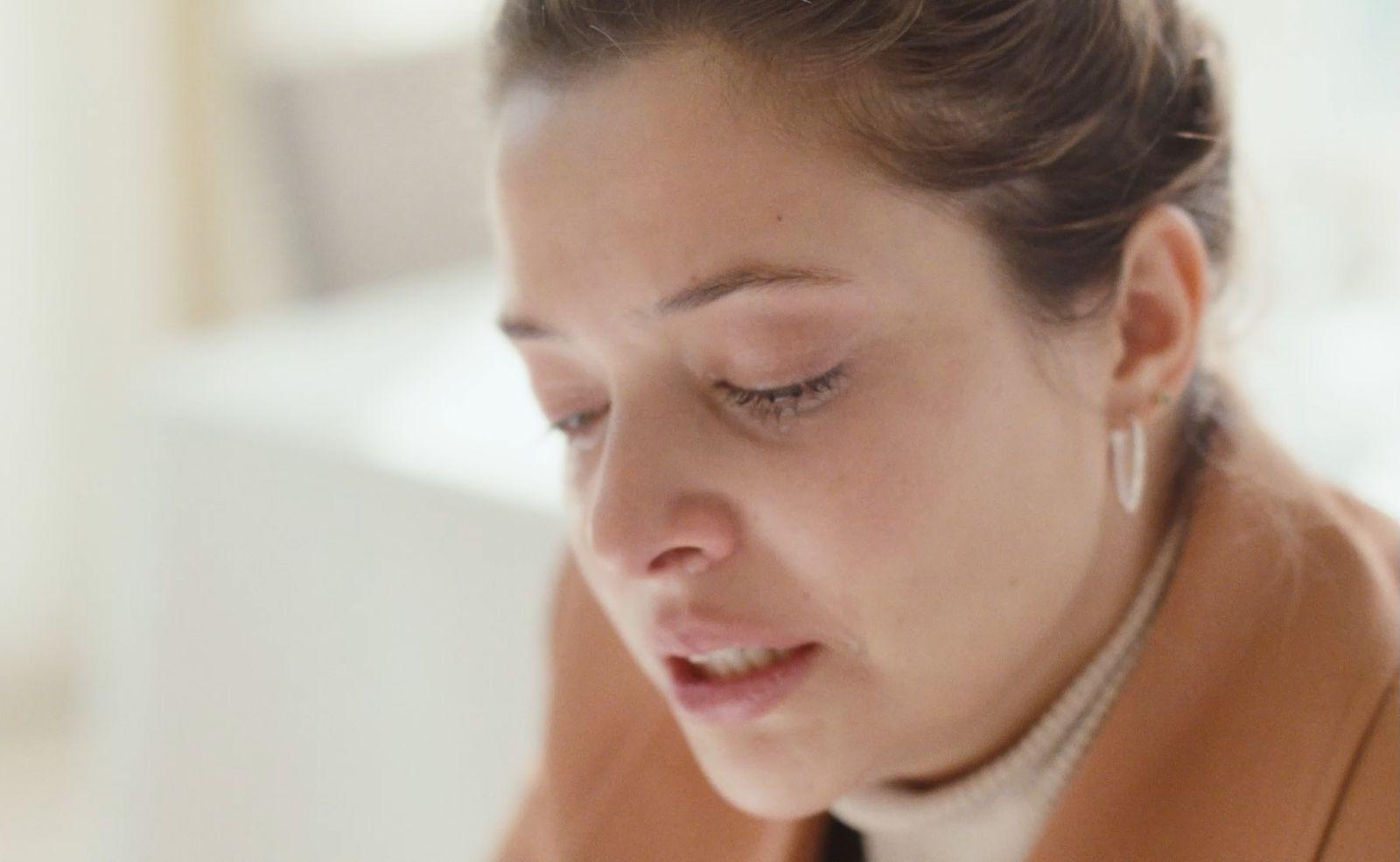 a woman in a brown jacket looking down at her cell phone