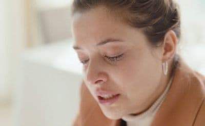 a woman in a brown jacket looking down at her cell phone