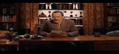 a man sitting at a desk in front of a book shelf
