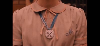 a person wearing a brown shirt and a blue ribbon around their neck