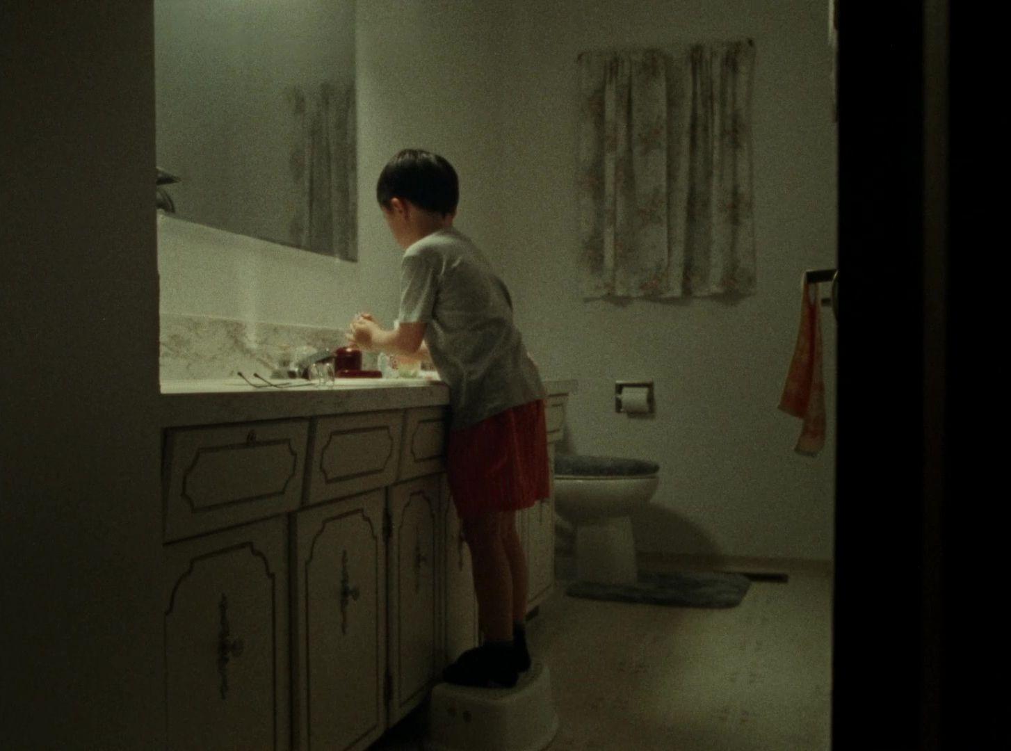 a boy standing on a toilet in a bathroom