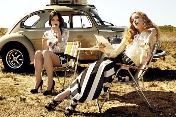 two women sitting in chairs in front of a car