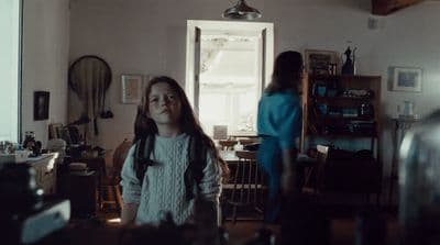 a young girl standing in a living room next to a window