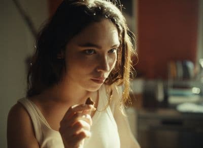 a woman in a white tank top is holding a piece of food
