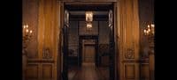 a hallway with a chandelier and a door leading to another room