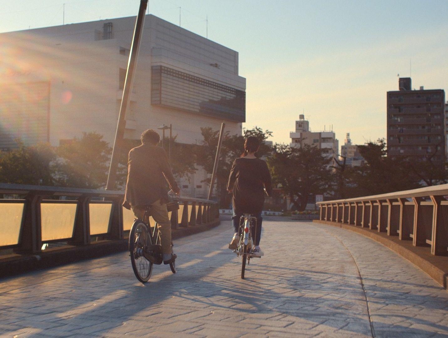 a couple of people riding bikes across a bridge