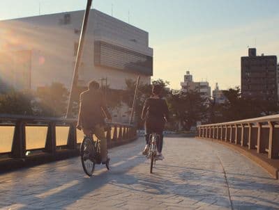 a couple of people riding bikes across a bridge