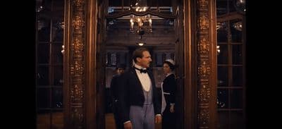 a man in a tuxedo standing in front of a mirror