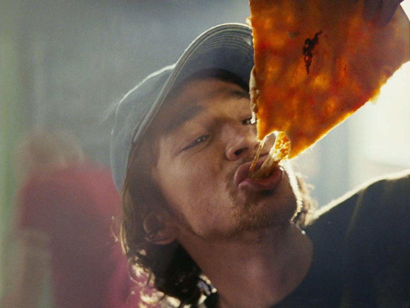 a man holding a slice of pizza up to his face