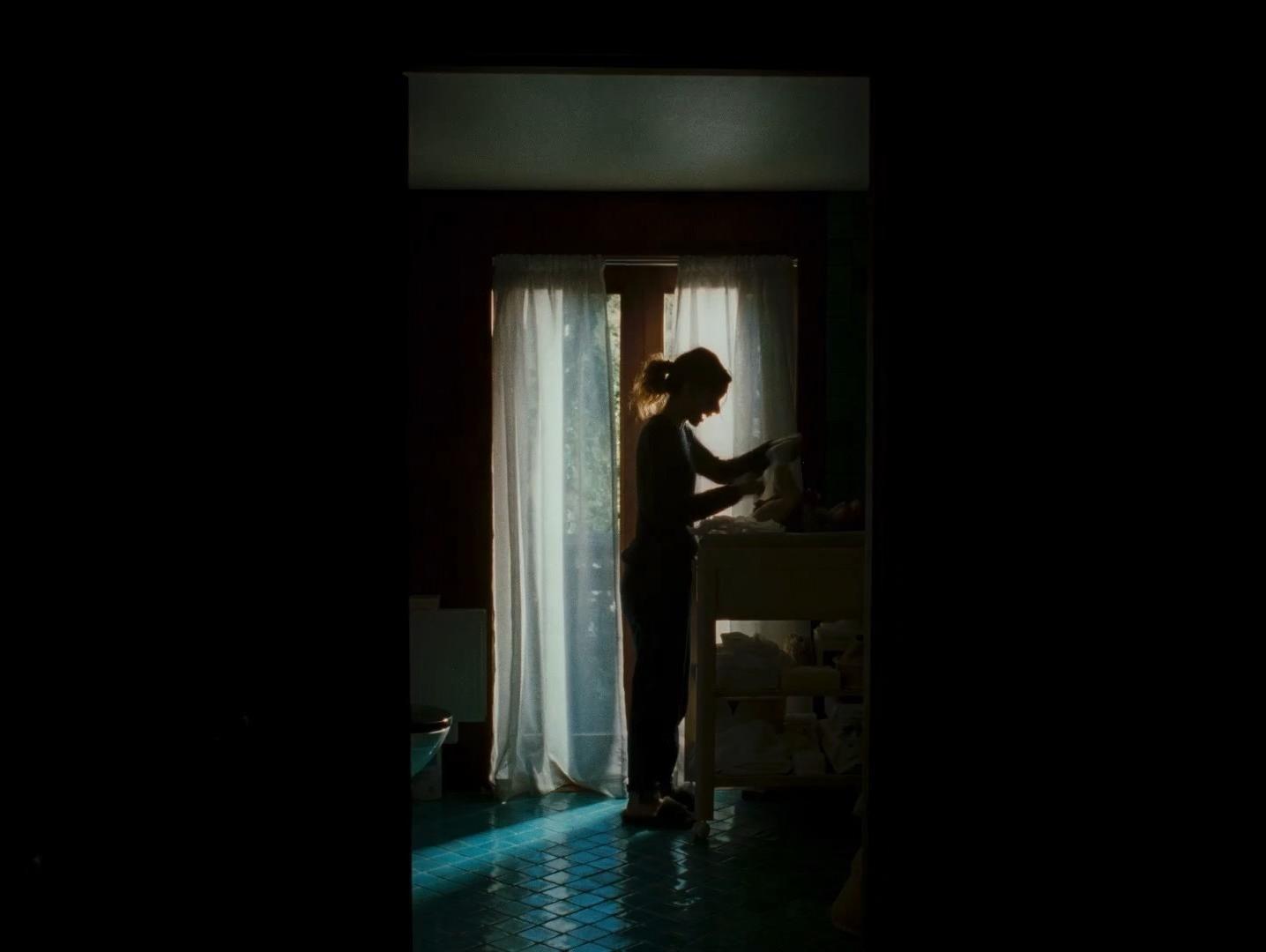 a woman standing in front of a window in a dark room