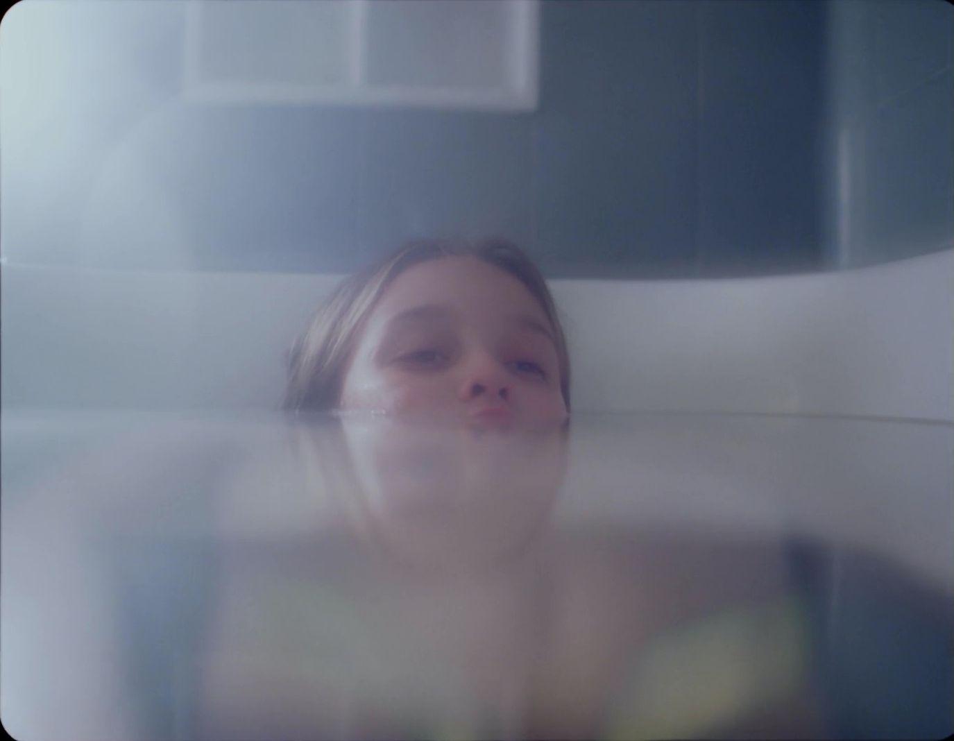 a young girl laying in a bed with her eyes closed