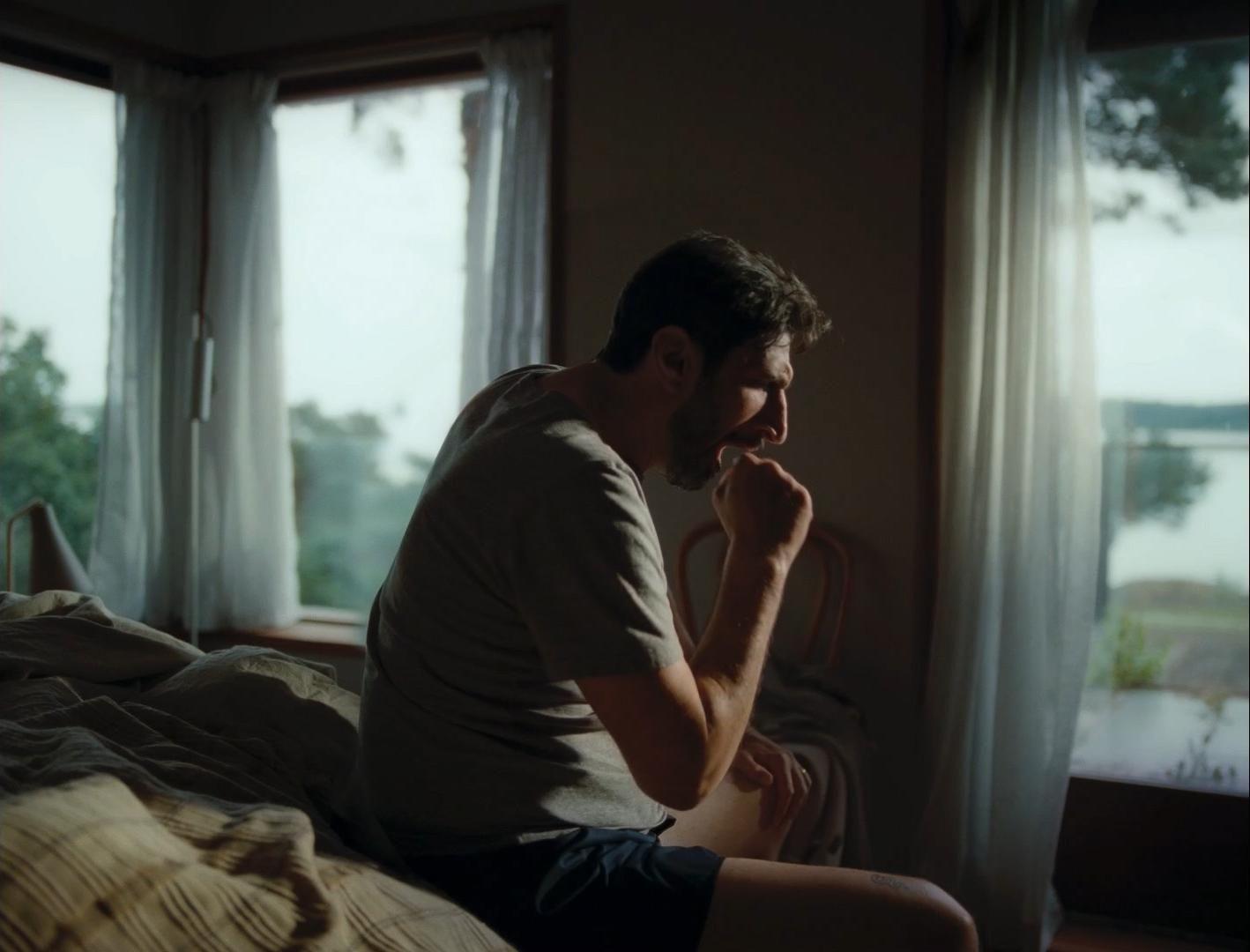 a man sitting on a bed in front of a window