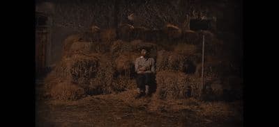 a man standing in front of a pile of hay