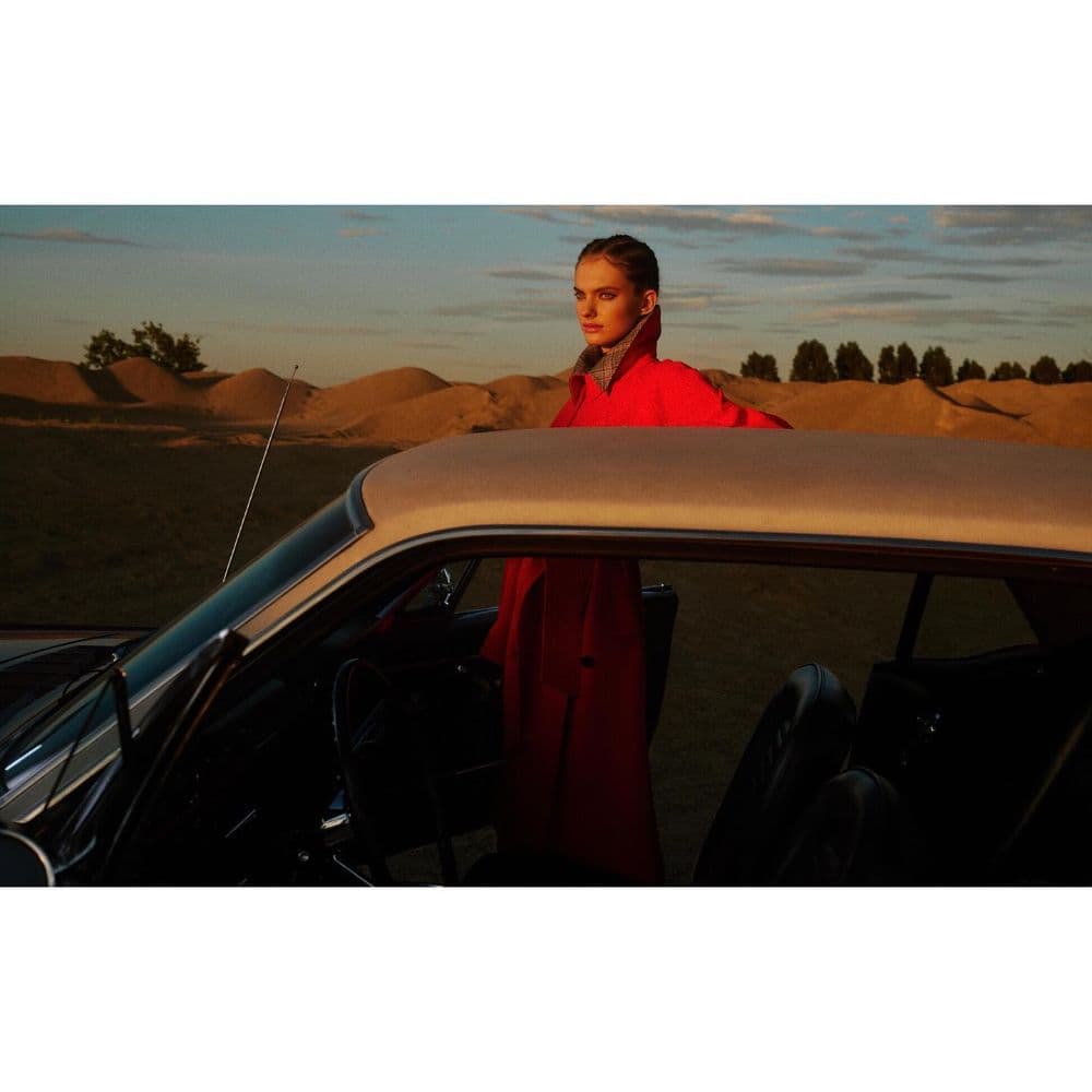 a woman standing next to a car in the desert