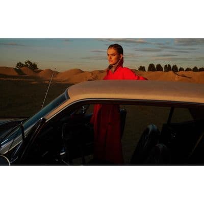 a woman standing next to a car in the desert